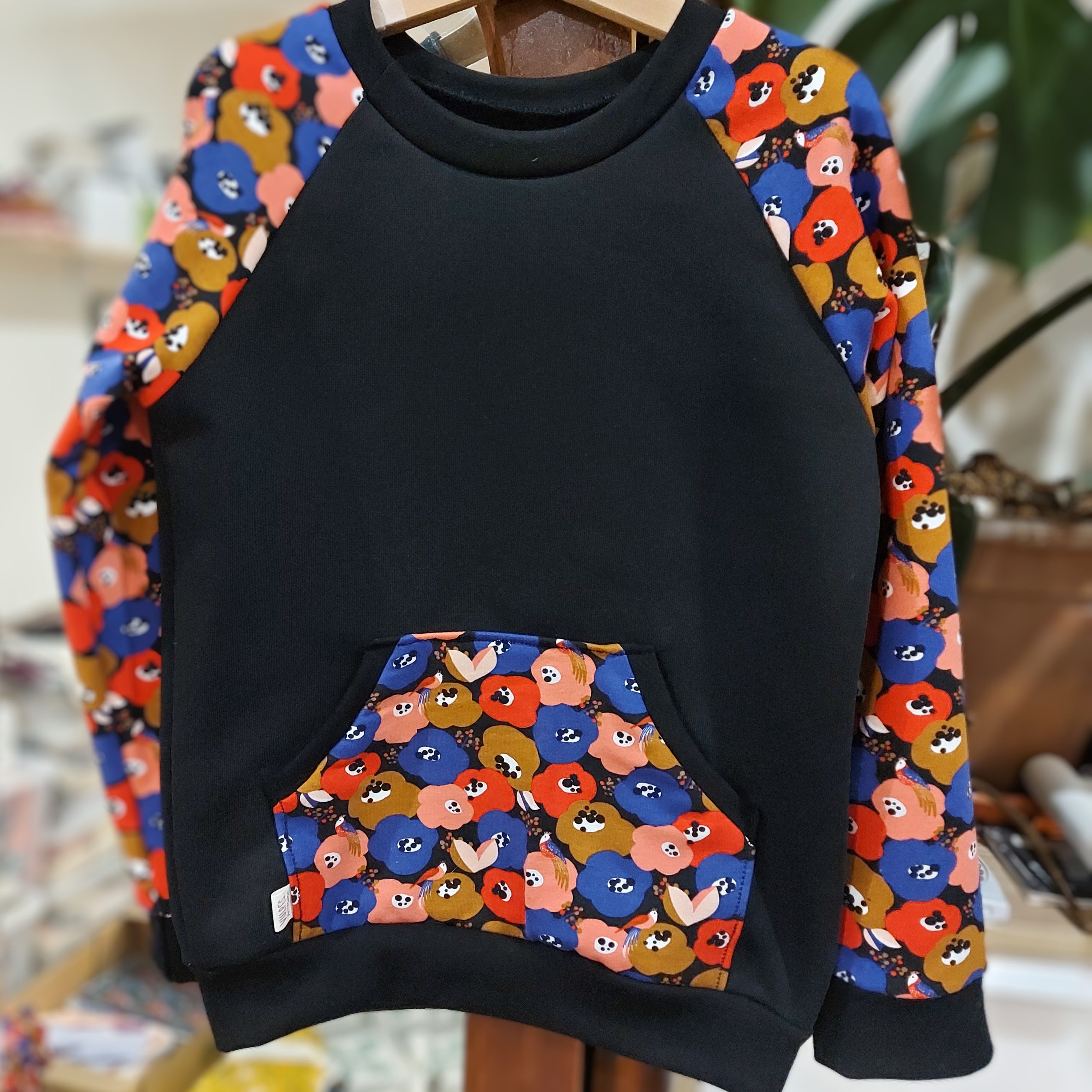 sudadera negra con amapolas rojas, moradas y rosas,